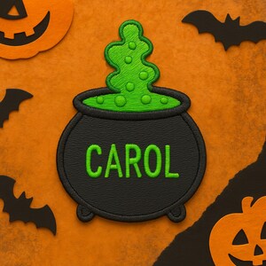 May include: A black cauldron patch with the name "CAROL" embroidered in green. The cauldron has green bubbling liquid spilling out. The background is orange with Halloween-themed cutouts of bats and pumpkins.