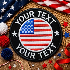 May include: A circular black patch featuring the American flag, with the text "YOUR TEXT" around the edge. The patch is displayed on a wooden surface, alongside star-shaped decorations and red ribbon.