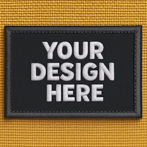 May include: A rectangular black patch with white embroidered text that reads "YOUR DESIGN HERE." The patch has a stitched border and is set against a textured yellow background.