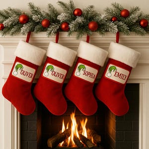 May include: Four red Christmas stockings with white cuffs hang from a mantel decorated with greenery and red ornaments. Each stocking has a personalized label with a name and a green graphic.