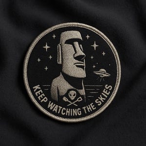 May include: Embroidered patch featuring a Moai statue, stars, and a UFO against a black background. The text "KEEP WATCHING THE SKIES" is embroidered around the edge. The patch has a circular shape with a stitched border.