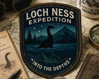 May include: A shield-shaped embroidered patch featuring a dark blue night scene of the Loch Ness monster in a lake with mountains and pine trees. The text reads LOCH NESS EXPEDITION at the top and INTO THE DEPTHS at the bottom in white lettering.