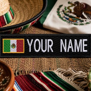 May include: A rectangular black embroidered patch featuring the Mexican flag on the left side and the white text "YOUR NAME" on the right. The patch has a stitched border and is designed for attachment to fabric items with its clear lettering.