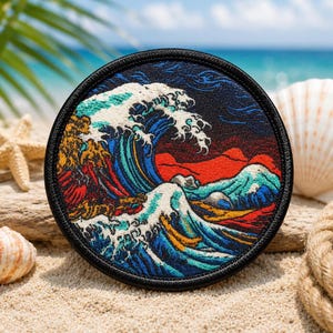 May include: A circular embroidered patch featuring a stylized ocean wave design. The artwork displays a large, cresting blue wave with white foam, set against a dark background with vibrant red and orange accents, finished with a black border.