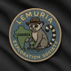 May include: Embroidered patch featuring a lemur wearing a hat, holding a hammer, and sitting next to a green map labeled "Lemuria." The patch reads "Lemuria Exploration Society" in a circular design with a blue background.