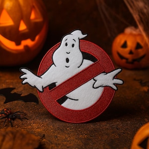 May include: A white ghost character patch with a red no-ghost symbol, ideal for Halloween. The patch features a cartoon ghost with an open mouth and outstretched arms. The background includes carved pumpkins and a spider.