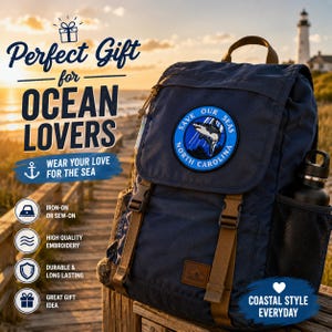 May include: A navy blue backpack with brown straps and a circular patch that reads "Save Our Seas North Carolina." The backpack has a side pocket holding a black water bottle. Text on the image says "Perfect Gift for Ocean Lovers."
