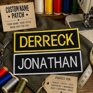 May include: Two rectangular embroidered patches on a dark fabric background. The top patch features the name DERRECK in yellow thread on a black background with a yellow border. The bottom patch features the name JONATHAN in white thread.
