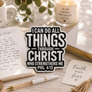 Może przedstawiać: Czarno-biała naszywka z napisem "I CAN DO ALL THINGS THROUGH CHRIST WHO STRENGTHENS ME PHIL 4:13". Naszywka leży na drewnianej powierzchni z długopisem, kubkiem, świecą i książką.