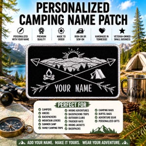 Op de afbeelding: Een rechthoekige zwarte geborduurde patch met witte stiksels van een bergketen, een opkomende zon, een kampvuur, een tent en twee gekruiste pijlen. De tekst YOUR NAME staat onderaan in het midden met een witte rand.