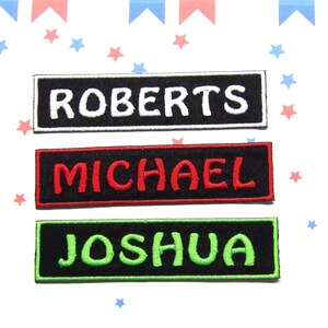 May include: Three black rectangular fabric patches with white, red, and green embroidered lettering. The patches read "ROBERTS", "MICHAEL", and "JOSHUA".