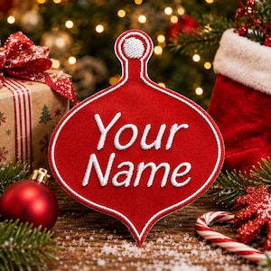 May include: A red, onion-shaped embroidered patch with a white border and a small white circle at the top. The text "Your Name" is stitched in white thread across the centre of the patch, which features a textured fabric finish throughout.