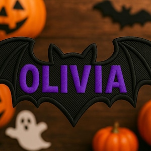 May include: Black bat-shaped applique with the name "OLIVIA" embroidered in purple. The Halloween-themed image includes orange pumpkins, a white ghost, and bat silhouettes, all set against a wooden background.