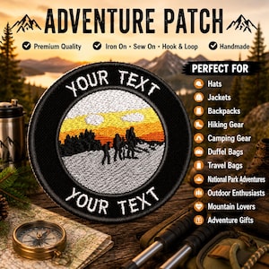May include: A circular embroidered patch featuring a black border with the text YOUR TEXT at the top and bottom. The center depicts a landscape with a white snowy foreground, black silhouettes of hikers, and an orange and yellow sunset sky.