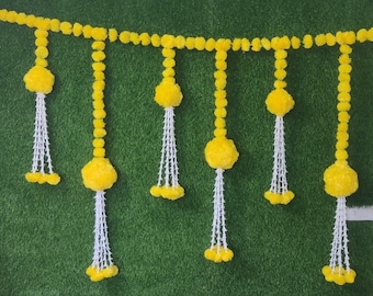 May include: A yellow flower garland with white strings hanging from it. The garland is made of small, round pom-poms and is ideal for decorating a home or event.