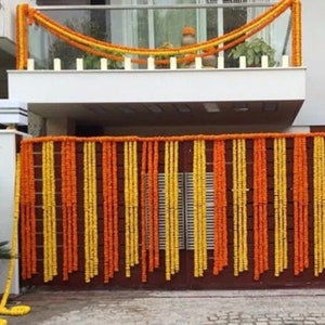 May include: A doorway decorated with garlands of yellow and orange marigold flowers. The garlands are strung in vertical rows, creating a colorful and festive display.