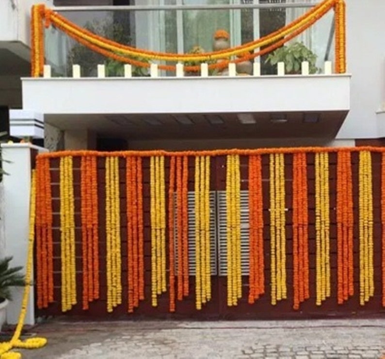 May include: A doorway decorated with garlands of yellow and orange marigold flowers. The garlands are strung in vertical rows, creating a colorful and festive display.