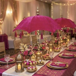 Pode incluir: Um centro de mesa em forma de guarda-chuva de veludo fúcsia com detalhes em filigrana dourada e borlas pendentes, apoiado por um suporte dourado com luzes integradas, sobre uma mesa com arranjos florais, lanternas e talheres.