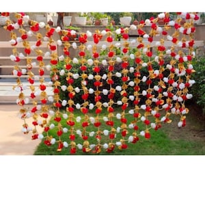May include: A garland of red, white, and gold artificial flowers. The garland is made of small, round flowers that are strung together in a grid pattern.