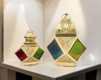 May include: Two gold metal lanterns with colorful glass panels. The larger lantern has a pointed top and the smaller lantern has a round top.