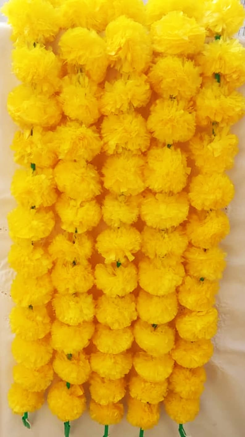 May include: A garland of yellow marigold flowers, strung together with green stems. The garland is made of artificial flowers and is perfect for decorating for a special occasion.