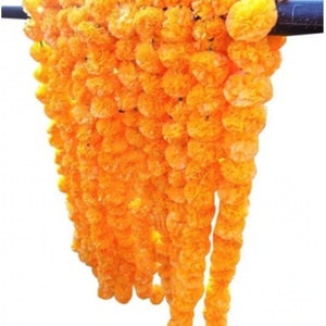 May include: A long garland of bright orange marigold flowers strung together. The garland is made of artificial flowers and is perfect for decorating for a festival or special occasion.