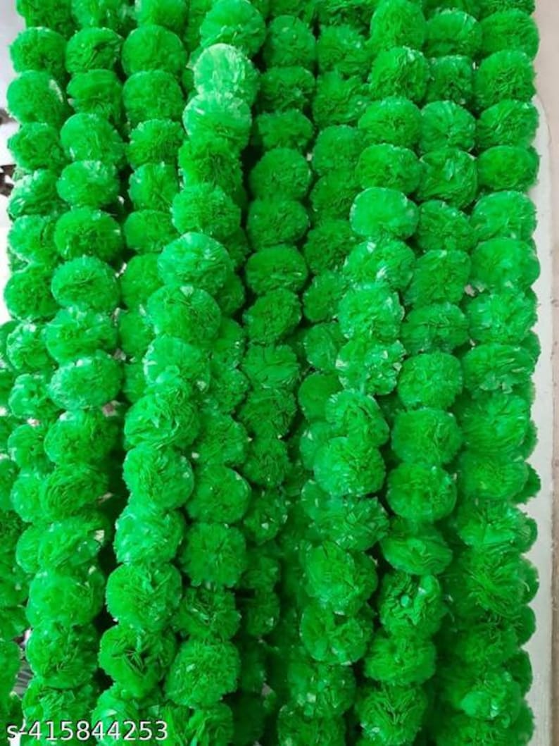 May include: A close-up of multiple strands of bright green, spherical artificial flower garlands. The garlands are densely packed, creating a textured, vibrant green backdrop. The flowers appear to be made of a soft, possibly fabric-like material.