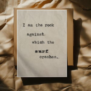 May include: A beige card with black text that reads "I am the rock against which the surf crashes."