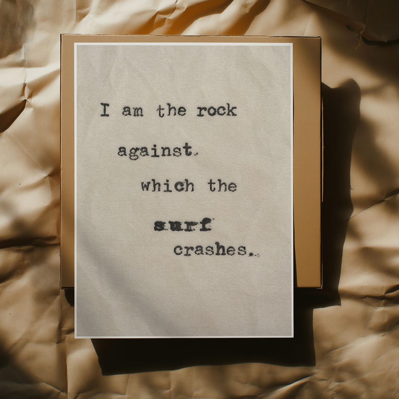 May include: A beige card with black text that reads "I am the rock against which the surf crashes."