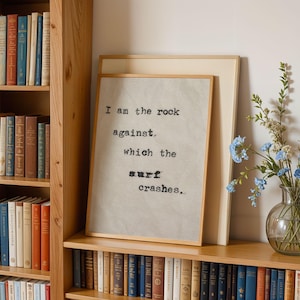 May include: A framed print with a quote about the ocean: "I am the rock against which the surf crashes..." The print is hanging on a wooden shelf with books and a vase of blue flowers.