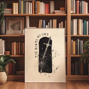 Pode incluir: Impressão de arte emoldurada com uma ilustração em preto e branco de uma espada dentro de um arco escuro, com o texto "YOU BOW TO NO ONE". A obra de arte é exibida em um fundo de uma estante de madeira cheia de livros.