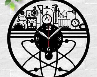 May include: Black and white laser cut clock design featuring a stylized atom with a clock face in the center. The clock face has Roman numerals and a black background. The clock is surrounded by a design of scientific equipment, including a beaker, a graduated cylinder, a pendulum, and a compass. The text "LASER CUTTING TEMPLATE" is at the top of the image. The text "AI CDR EPS SVG PDF DXF PNG" is at the bottom of the image.