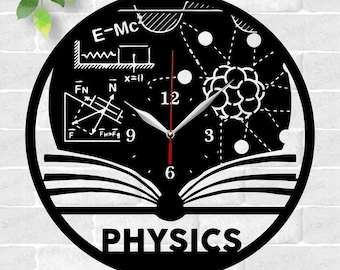 May include: Black and white laser cut clock design featuring a book with the word "PHYSICS" underneath. The clock face includes physics formulas and symbols, including E=MC, a diagram of forces, and an atom.