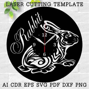May include: Black and white laser cut clock design featuring a stylized rabbit with the word "Rabbit" written in a decorative font. The clock face has Roman numeral markings for the hours.
