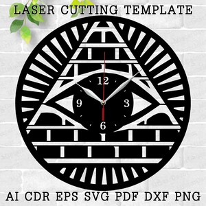 May include: A black and white laser cut clock template featuring an all-seeing eye inside a pyramid. The clock face has Roman numerals and the text "LASER CUTTING TEMPLATE".