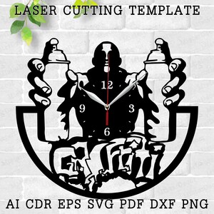May include: Black and white silhouette of a person holding two spray paint cans, with a clock face in the center. The clock face has black hands and a black background with white numbers. The text "Graffiti" is written in a stylized font below the clock face. The image is a laser cutting template.