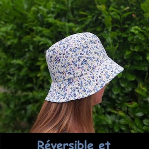 Peut inclure: Un chapeau bob blanc avec un motif floral bleu. Le chapeau est réversible et personnalisable. Le texte "Réversible et personnalisable" est imprimé en bas de l'image.