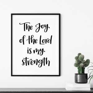 Op de afbeelding: Zwart-witte ingelijste print met de tekst "The Joy of the Lord is my strength".