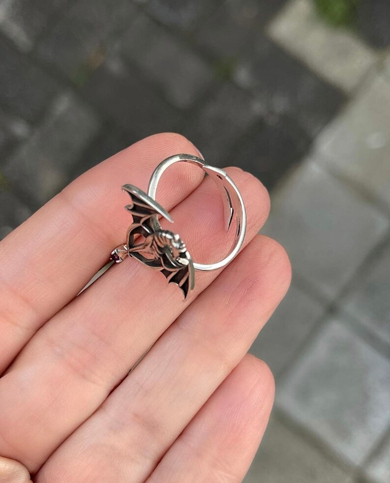 May include: A silver ring featuring a detailed design of a bat with its wings outstretched.