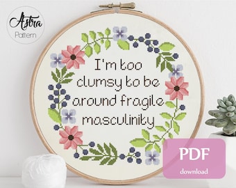 以下が含まれることがあります： 花輪と「I'm too clumsy to be around fragile masculinity」というテキストが書かれたクロスステッチパターン。このパターンは14カウントのアイダ生地用で、9 x 8.9インチ（22.9 x 22.5 cm）です。