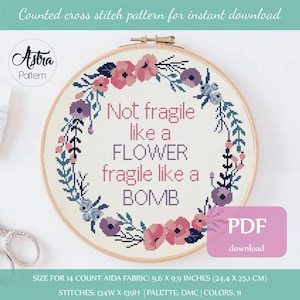以下が含まれることがあります： 花輪と「Not fragile like a FLOWER fragile like a BOMB」というテキストが描かれたクロスステッチパターン。このパターンは14カウントのアイダ生地用で、9.6 x 9.9インチ（24.4 x 25.1 cm）です。