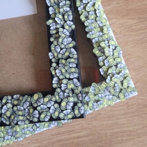 May include: Two black picture frames with a decorative border of yellow and white butterflies. The frames are stacked on top of each other.