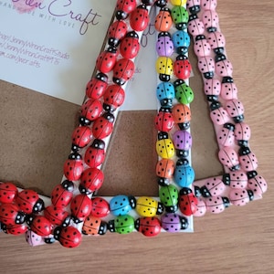 May include: Three decorative picture frames, each adorned with colorful ladybug embellishments. One frame features red ladybugs, another has a rainbow of colors, and the third is decorated with pink ladybugs. The frames are white with a wooden backing.