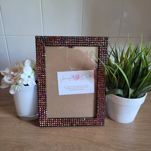 May include: A black picture frame with a brown background and a border of iridescent rhinestones. The frame is decorated with the text "Jenny Wren Craft Handmade with Love" and website information.