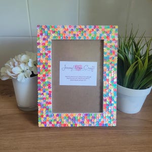 May include: A colourful picture frame with a white background and a business card that says "Jenny Wren Craft Handmade with Love". The frame is decorated with small, colourful, iridescent sequins.