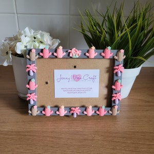Peut inclure: Un cadre photo gris décoré d'embellissements en cactus et palmiers roses et beiges. Le cadre a un fond en liège et comprend une carte de visite pour "Jenny Wren Craft Handmade with Love".