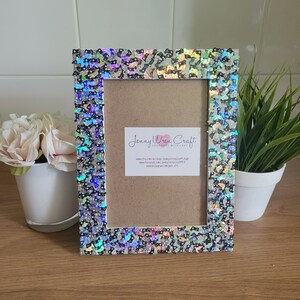 May include: A white picture frame with a black and iridescent glitter design. The frame has a brown mat and a card inside with the text "Jenny Wren Craft Handmade with Love" and contact information.