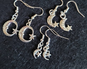May include: A set of four silver earrings featuring crescent moons and stars. The earrings are delicate and have a simple design.