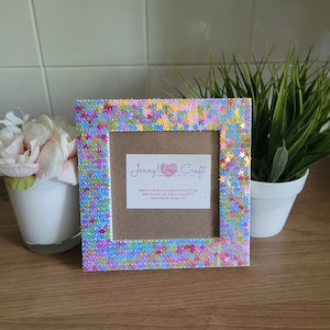May include: A white picture frame with a colourful floral design made of sequins. The frame has a brown cardboard insert with the text "Jenny Wren Craft Handmade with Love" and website information.