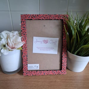 May include: A rectangular picture frame with a floral design in coral and black. The frame has a cardboard backing and a white label with the text "Jenny Wren Craft". A small white label at the bottom says "Please peel the protective film on both sides before use".
